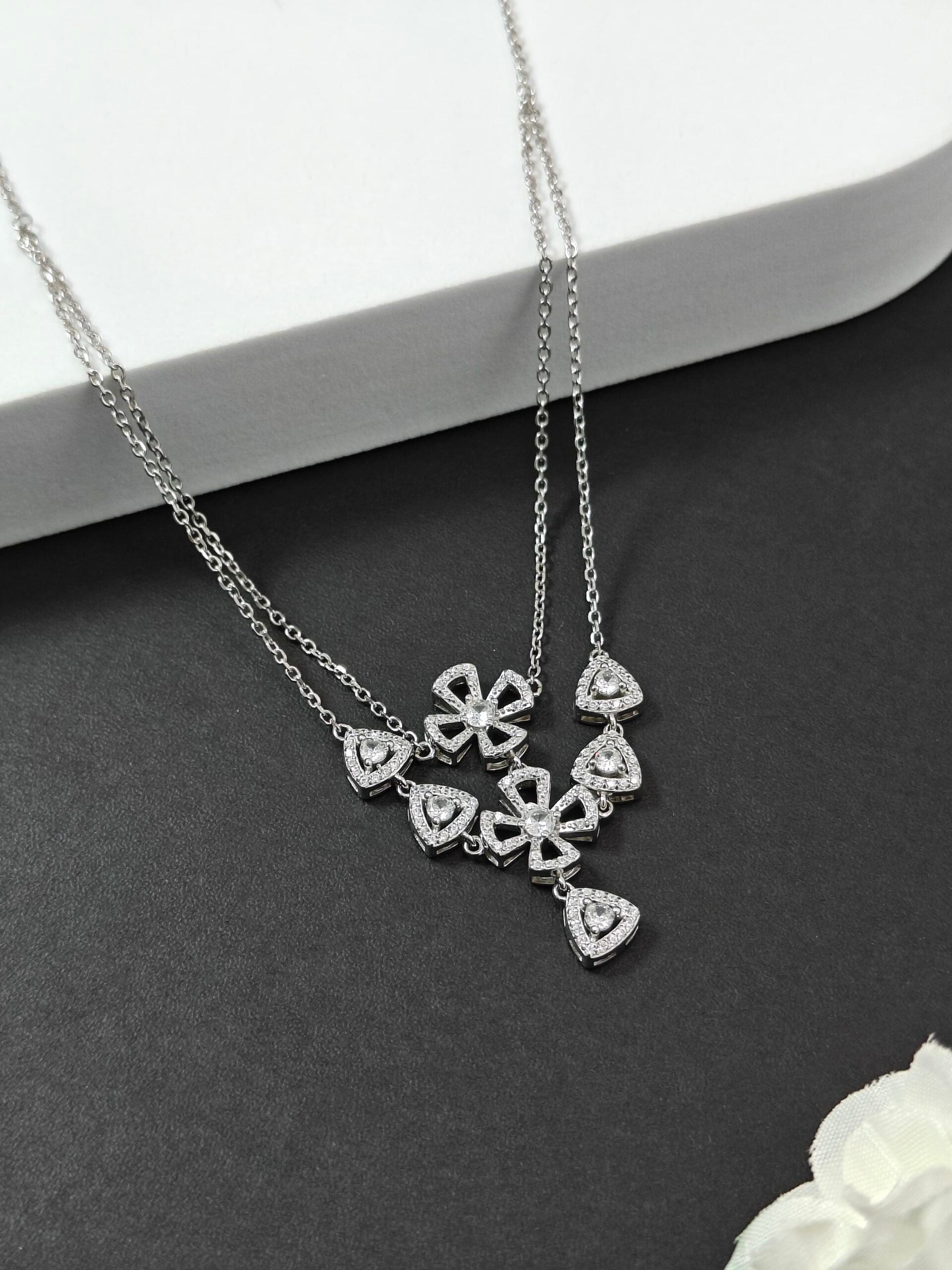 Silver necklace with heart-shaped pendants on a dark surface